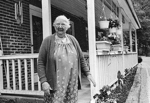 Patience Easton, mill worker, on the porch of her home built for mill workers, Oella