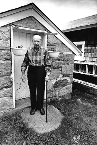 Russell Moxley, town policeman, outside his springhouse, Ellicott City
