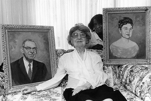 Gertrude Caplan, owner of Caplans furniture store, with portraits of herself and husband Sam, and nursing aide, Ellicott City