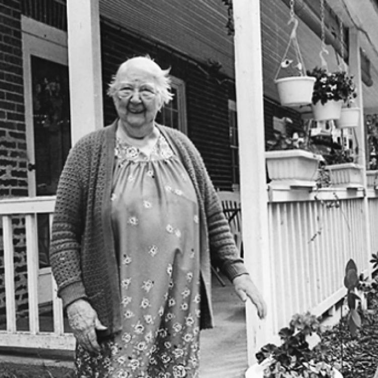 Patience Easton, mill worker, on the porch of her home built for mill workers, Oella