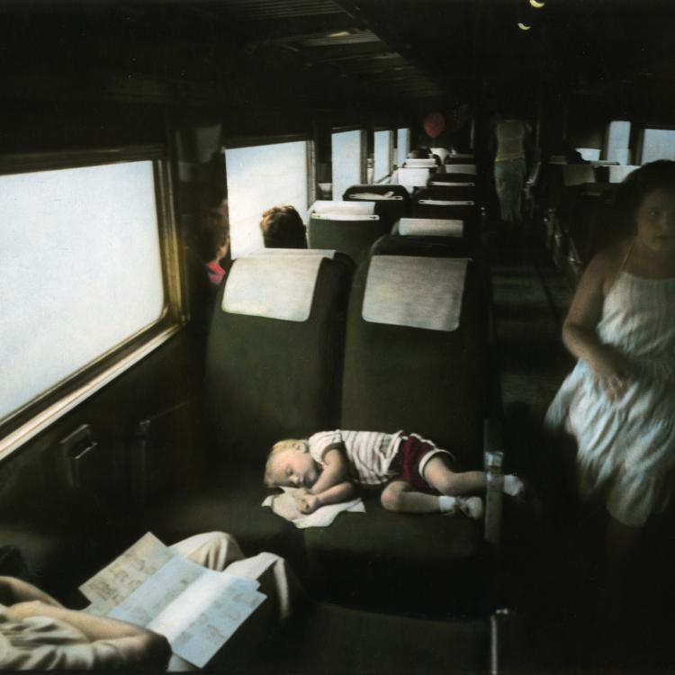 Sleeping boy on train. Handcolored gelatin silver print